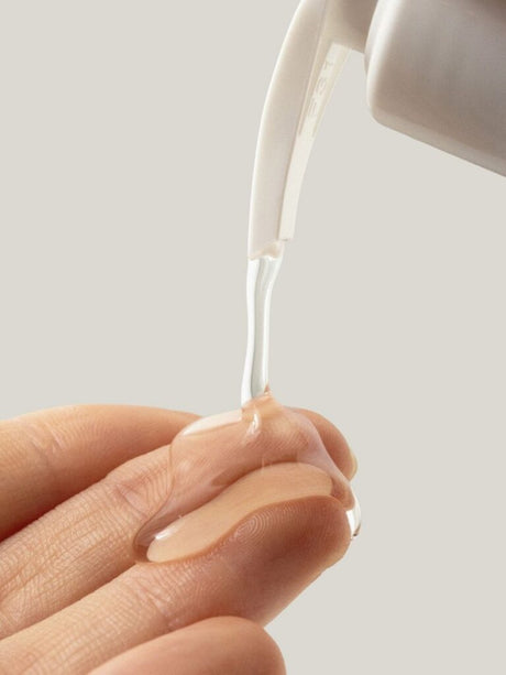 Caurspīdīgā dušas želejas tekstūra tiek izspiesta uz pirksta no pumpja